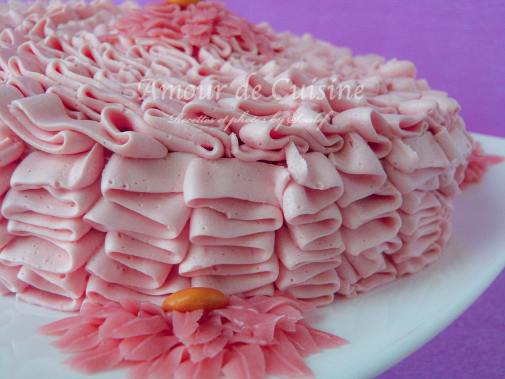 CBMS: Close-up of a cake covered in pink Swiss Meringue Buttercream frosting, decorated with elegant ruffles and flower-shaped details for a smooth, professional look