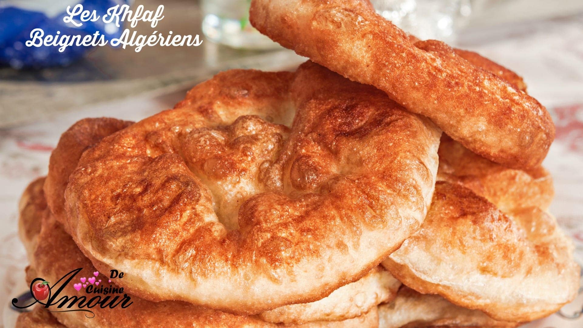 Sfenj algériens dorés et bien gonflés empilés sur une assiette, avec une texture moelleuse et une croûte légèrement croustillante après friture.