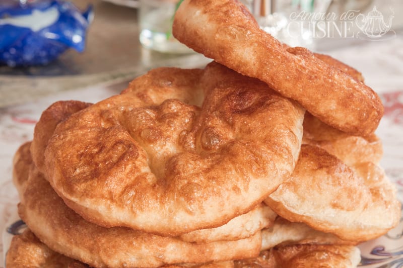 Sfenj maison dorés et moelleux empilés sur une assiette, avec une texture légère et gonflée après friture.