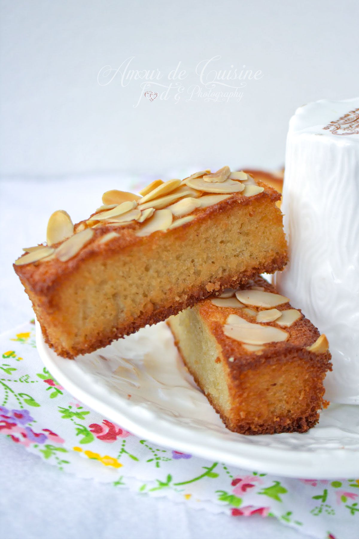 Financiers aux amandes moelleux et dorés, garnis d’amandes effilées, servis avec une tasse blanche pour le goûter.