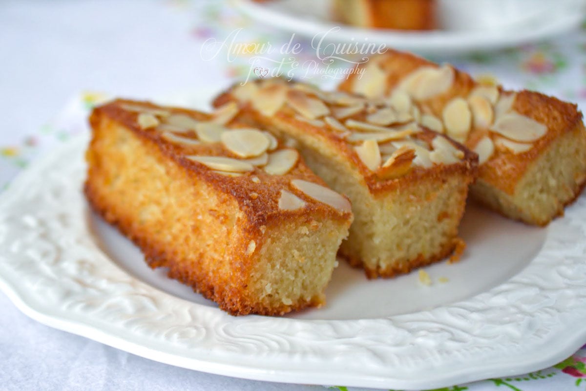 Financiers aux amandes moelleux, dorés sur les bords et décorés d’amandes effilées, présentés dans une assiette blanche.
