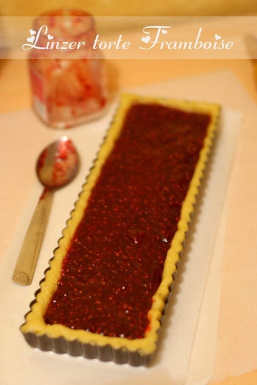 fond de la pate sablee aux amandes foncé dans un moule à tarte et garni de confiture de framboises