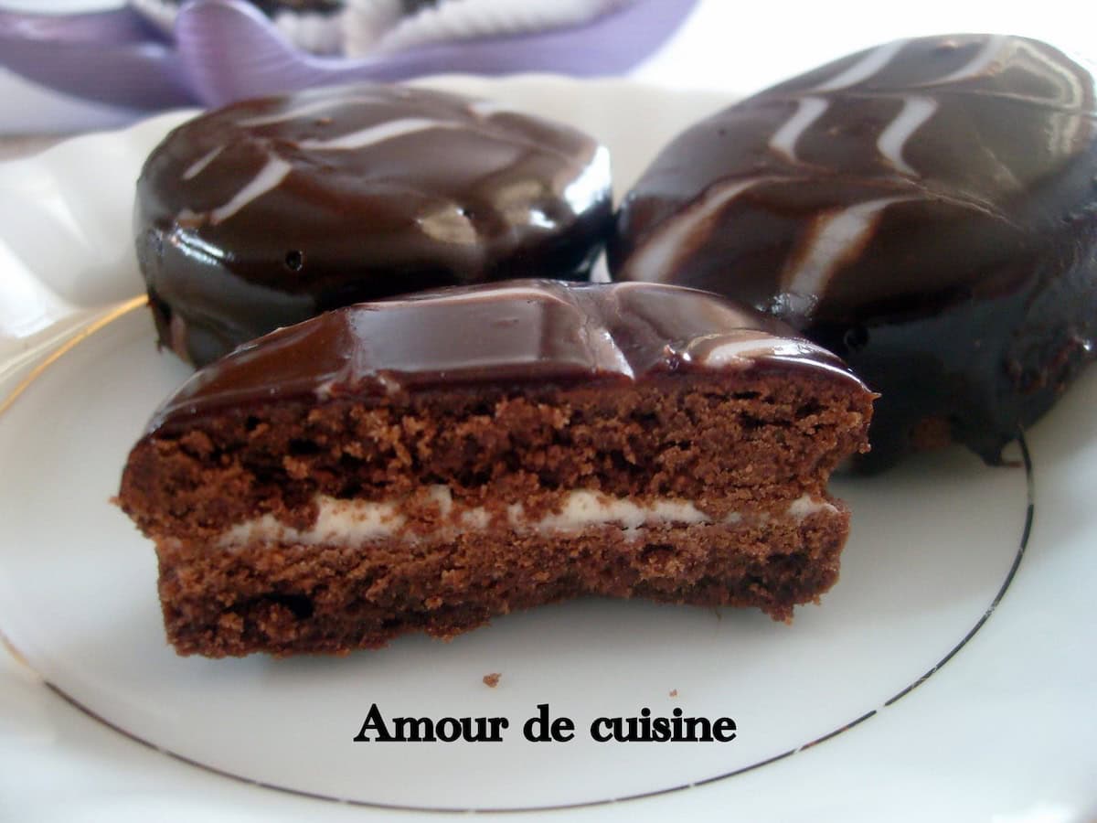 Sablés au chocolat fourrés à la crème et nappés d’un glaçage brillant, avec une coupe montrant la texture fondante.