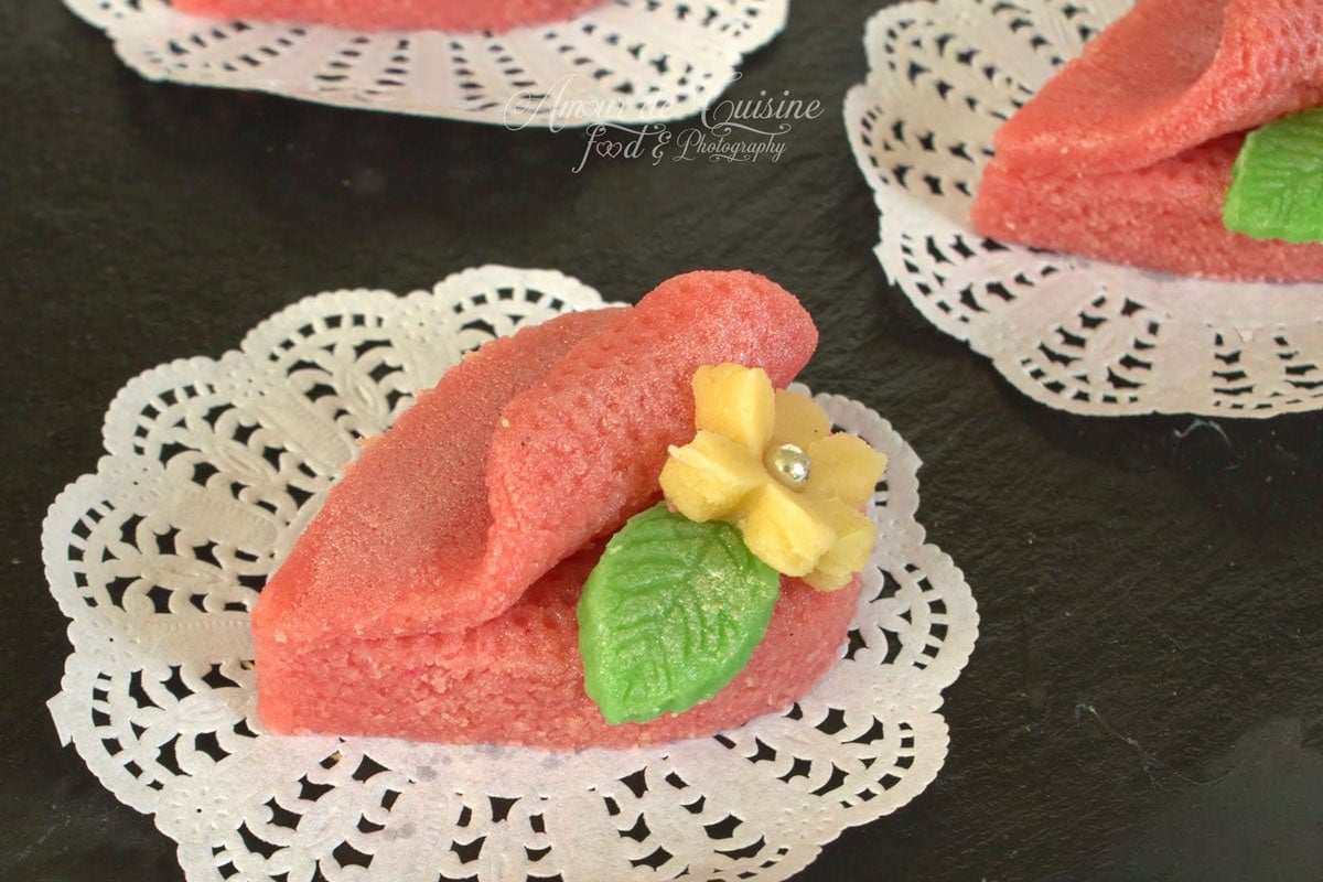 Harissa aux amandes, gâteau algérien fondant rose décoré d’une fleur jaune et d’une feuille verte en pâte d’amandes.