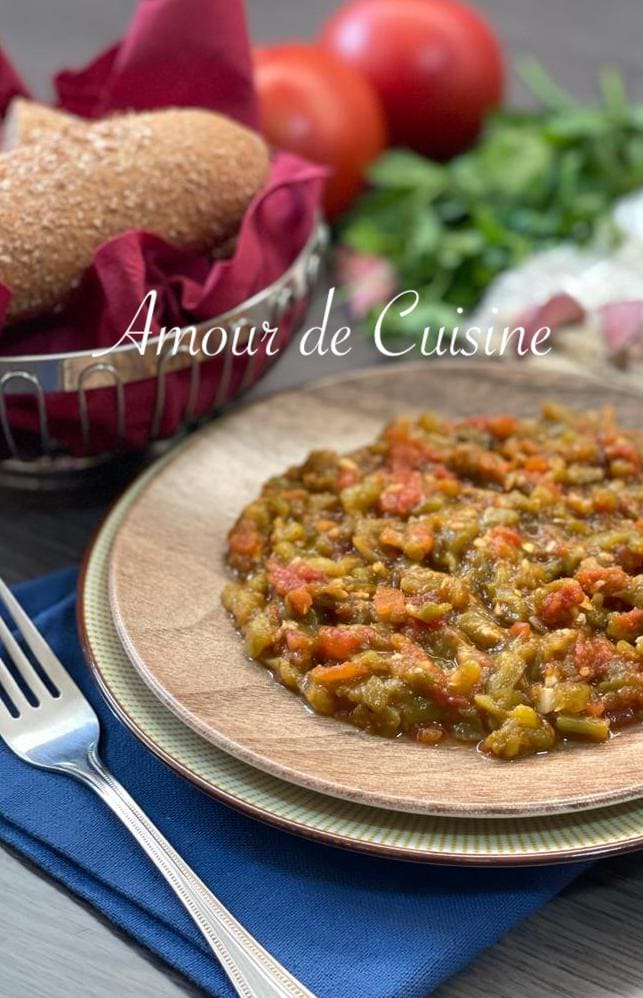 Salade méchouia ou hmiss aux poivrons grillés et tomates, présentée avec du pain croustillant, des tomates fraîches et des herbes.