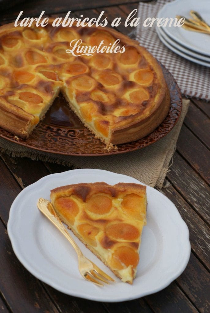 Tarte maison aux abricots frais et crème pâtissière, présentée sur une table en bois rustique, avec une part servie en gros plan dans une assiette blanche — dessert d'été simple et gourmand.