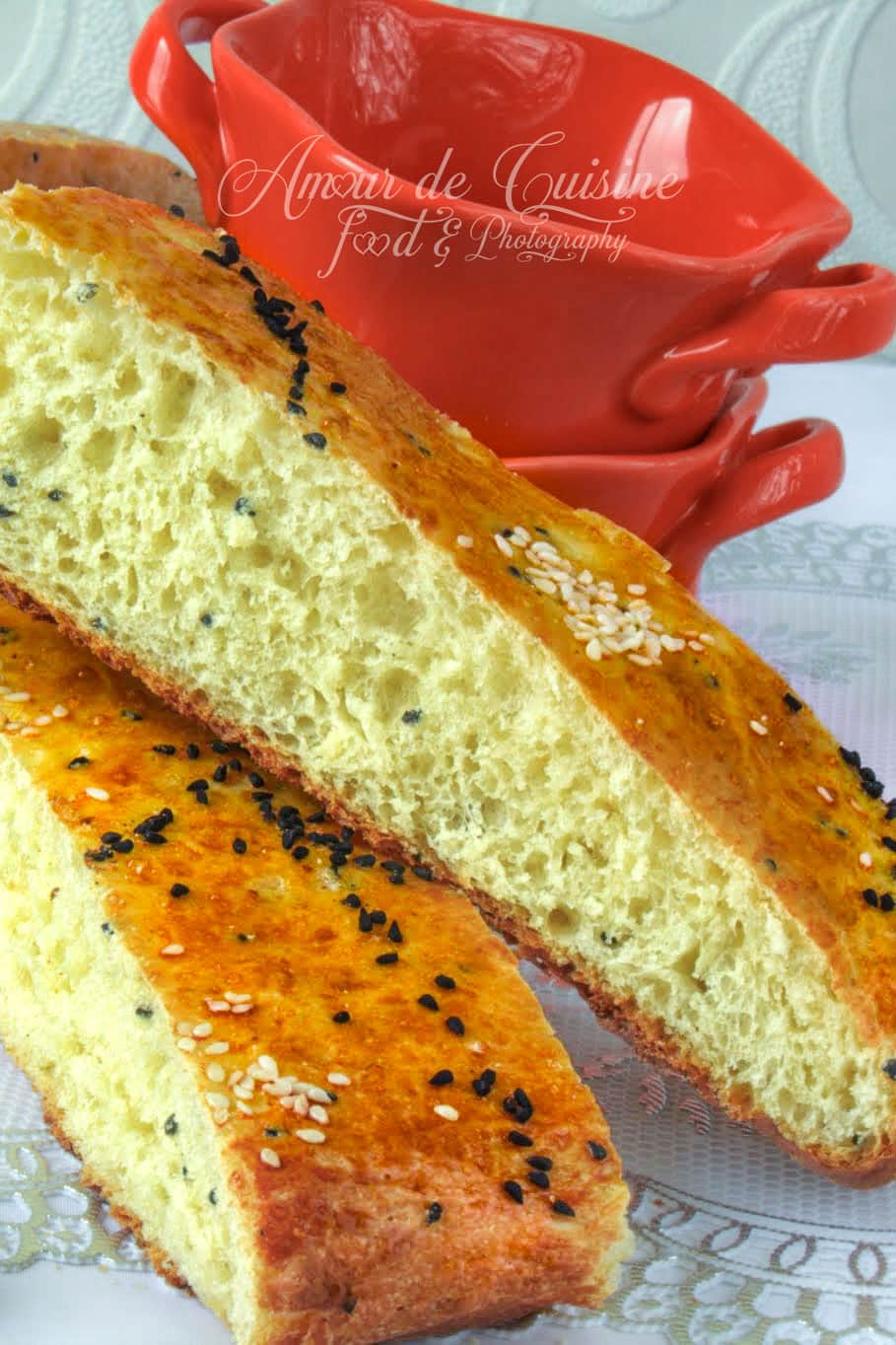 Khobz dar constantinois coupé en tranches, à la mie moelleuse et aérée, doré au four et parsemé de graines de nigelle et de sésame.