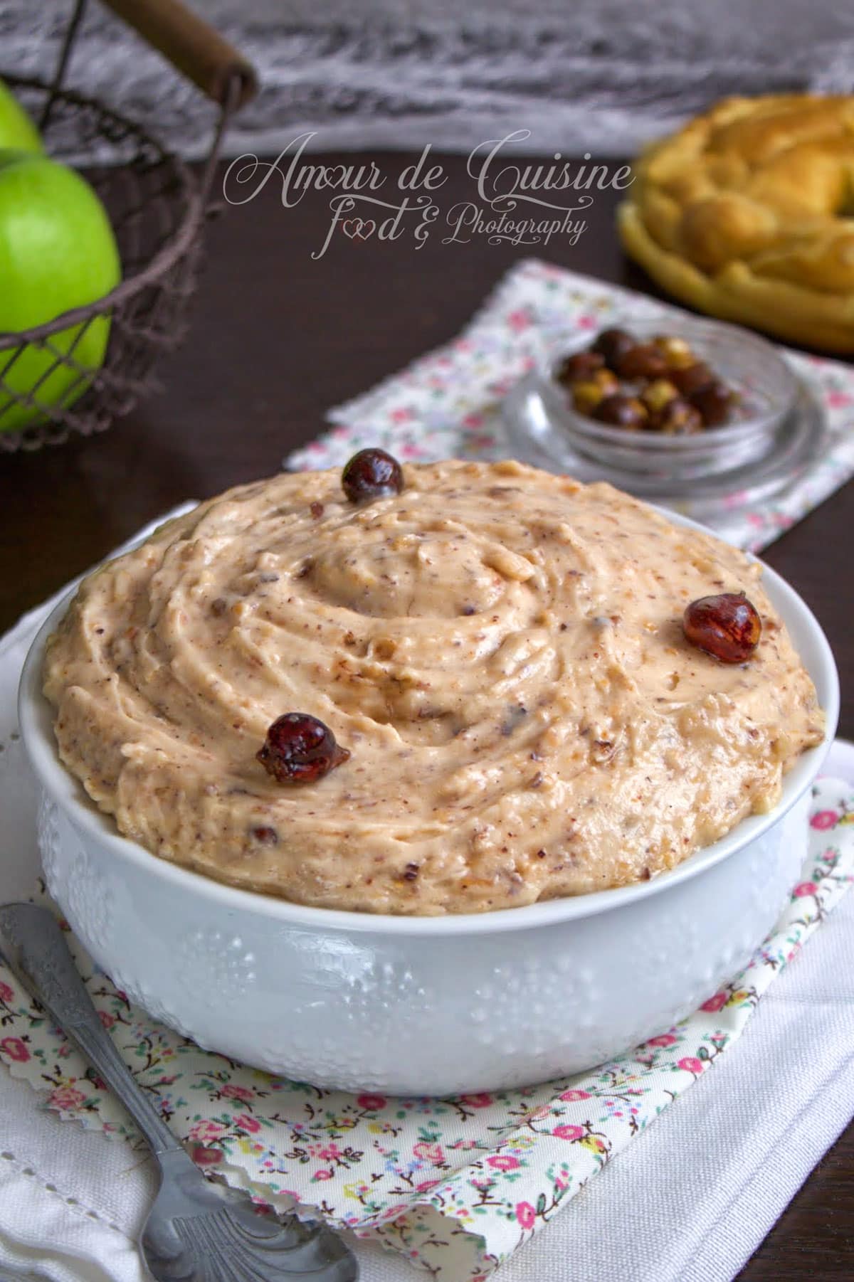 Crème mousseline praliné maison dans un bol blanc, garnie de noisettes caramélisées, avec une texture épaisse et onctueuse pour Paris-Brest.