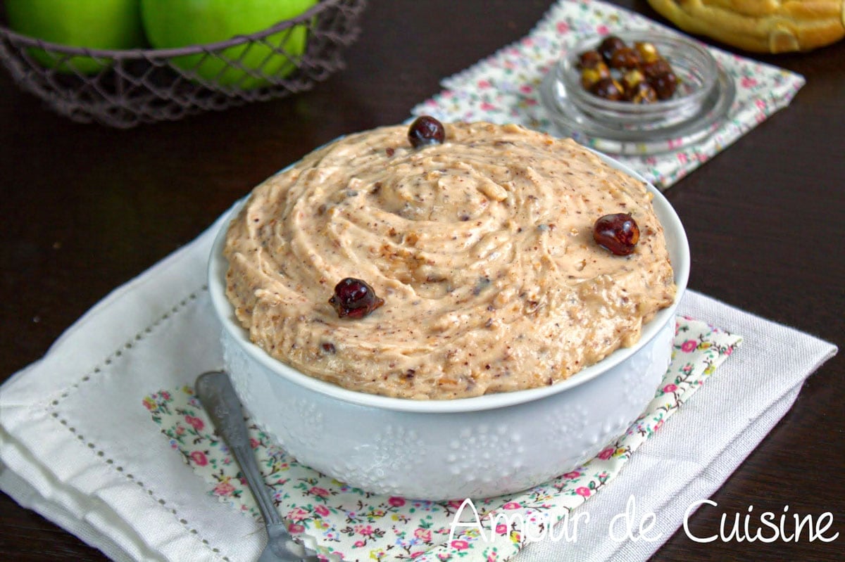 Crème mousseline praliné aux noisettes dans un bol blanc, décorée de noisettes caramélisées, avec une texture épaisse et lisse pour garnir les desserts.