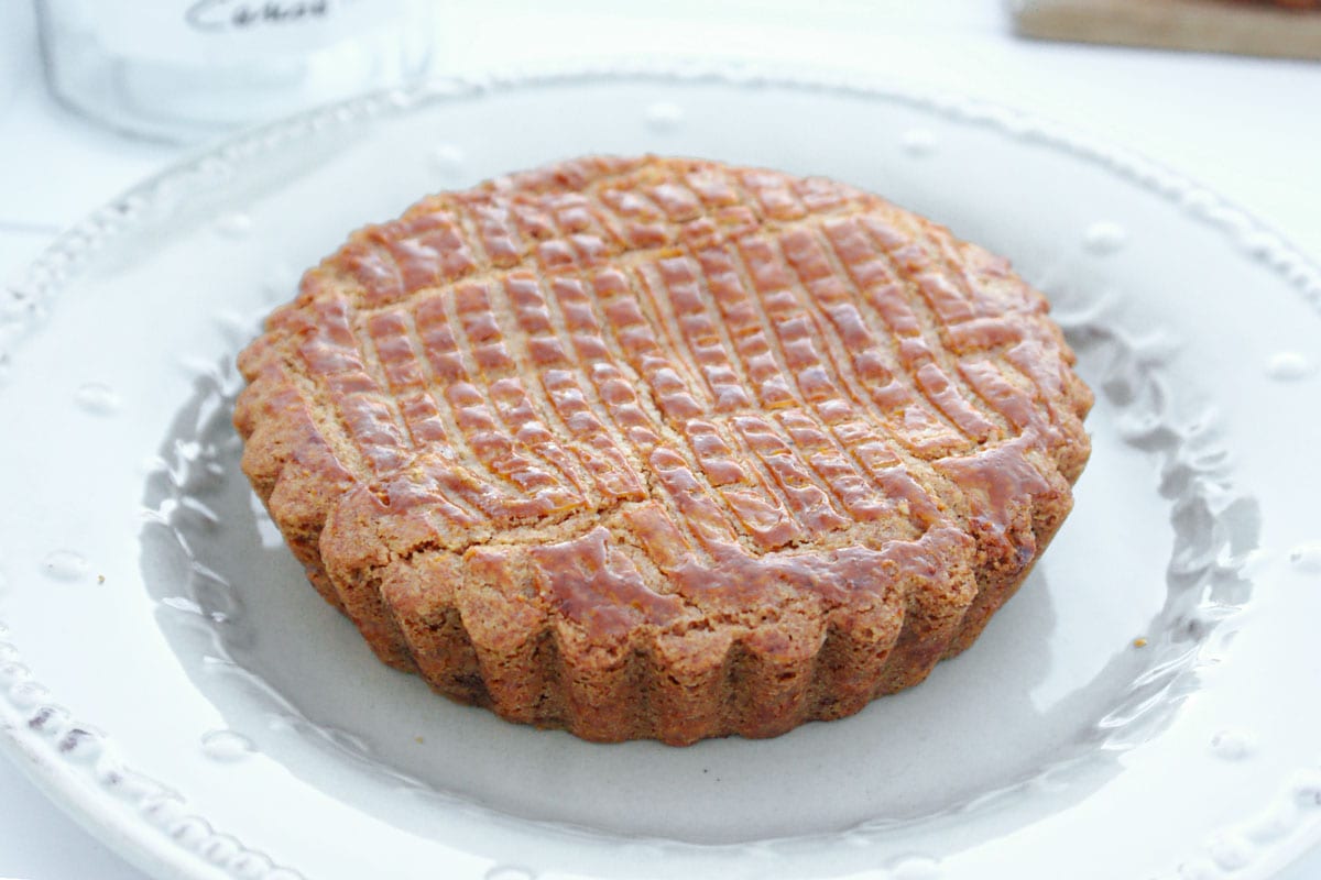 Gâteau basque individuel à la confiture de cerises noires, doré au four avec motifs quadrillés sur le dessus, servi dans une assiette.