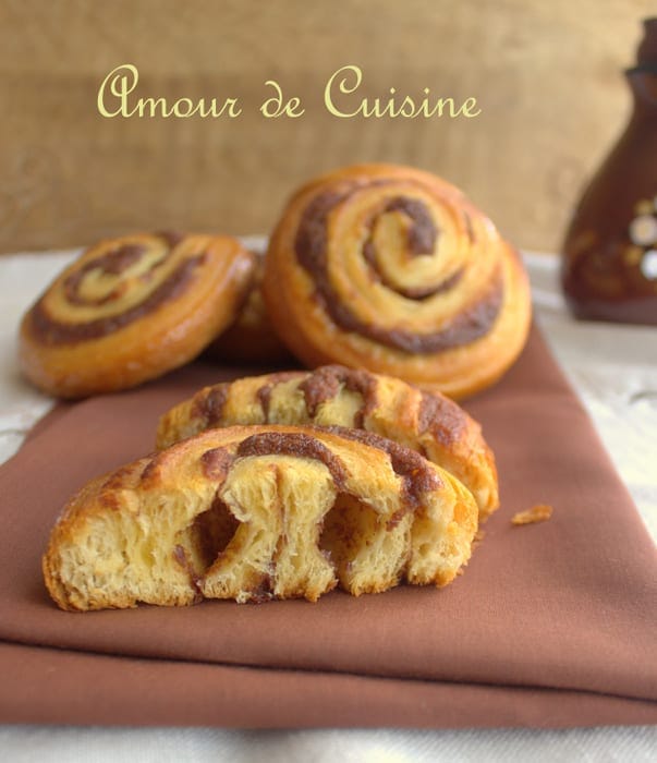 Intérieur d’un roulé à la cannelle maison coupé en deux, montrant sa pâte feuilletée levée bien aérée et sa garniture à la cannelle – viennoiserie moelleuse signée Amour de Cuisine