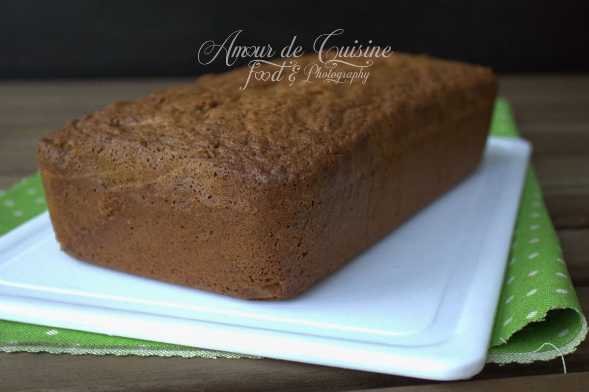 Cake à la pistache maison entier, gâteau moelleux cuit dans un moule rectangulaire, posé sur un plateau blanc avec serviette verte, recette facile et parfumée aux fruits secs