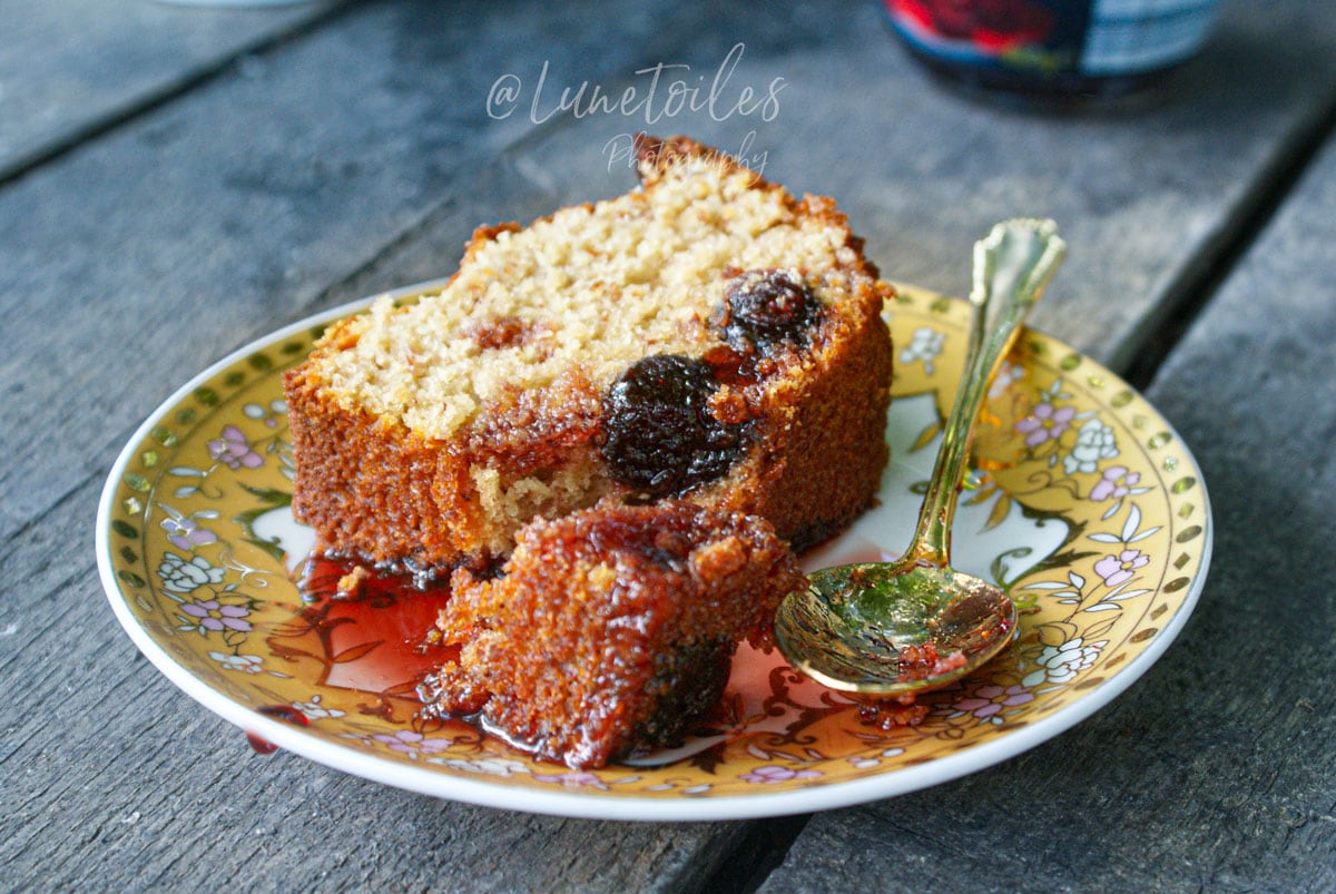 Part de gâteau aux cerises Amarena moelleux au yaourt et aux amandes, servie avec du sirop de cerises