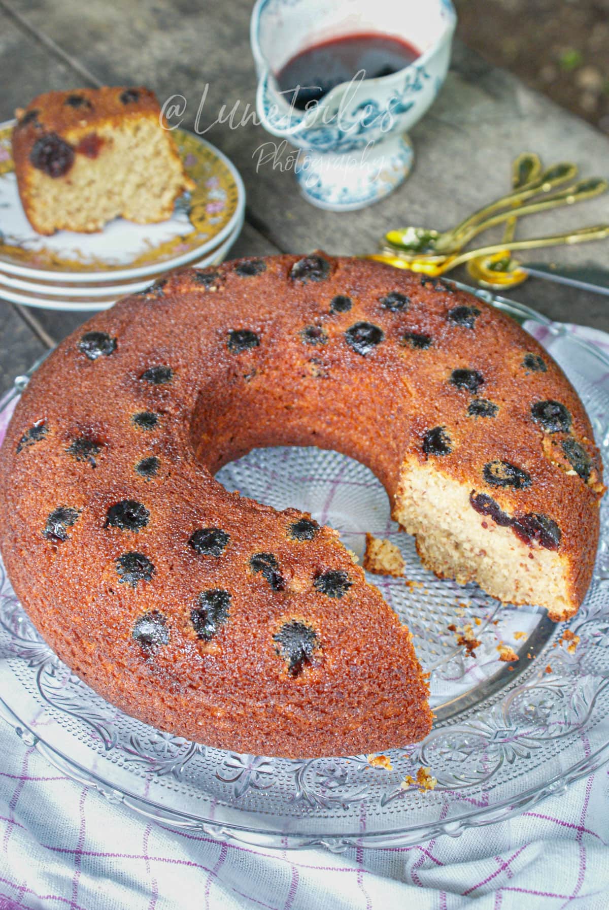 Gâteau aux cerises Amarena moelleux au yaourt et aux amandes, présenté en couronne sur un plat en verre