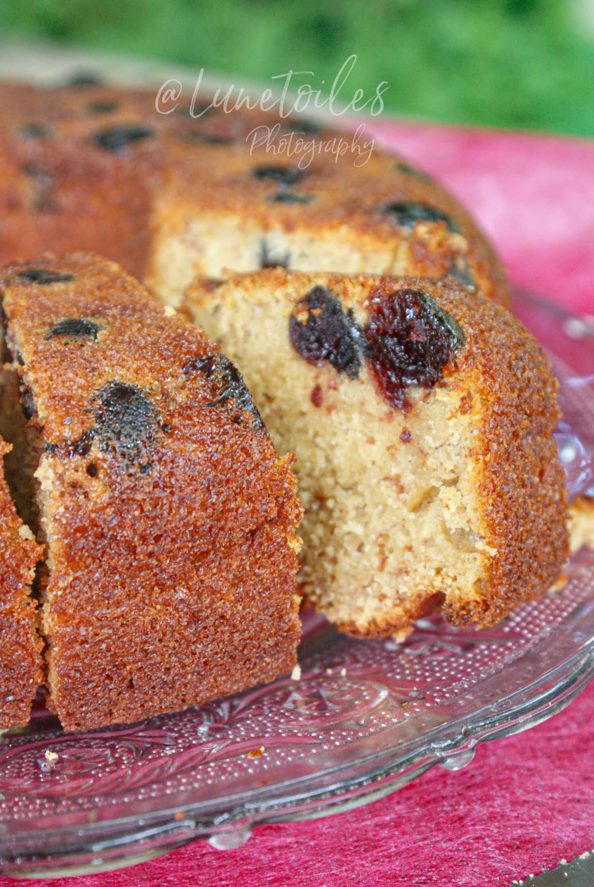 Gâteau aux cerises Amarena moelleux au yaourt et aux amandes, coupé en parts sur un plat en verre