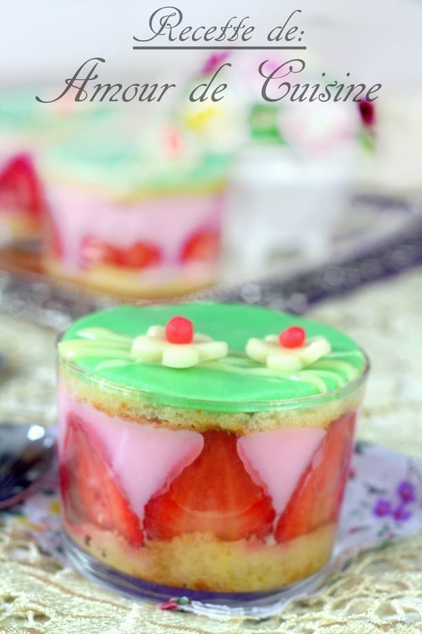 Verrine de pudding aux fraises façon fraisier, avec génoise moelleuse, fraises fraîches et glaçage vert décoré de fleurs en pâte d’amande, servie sur nappe dorée fleurie