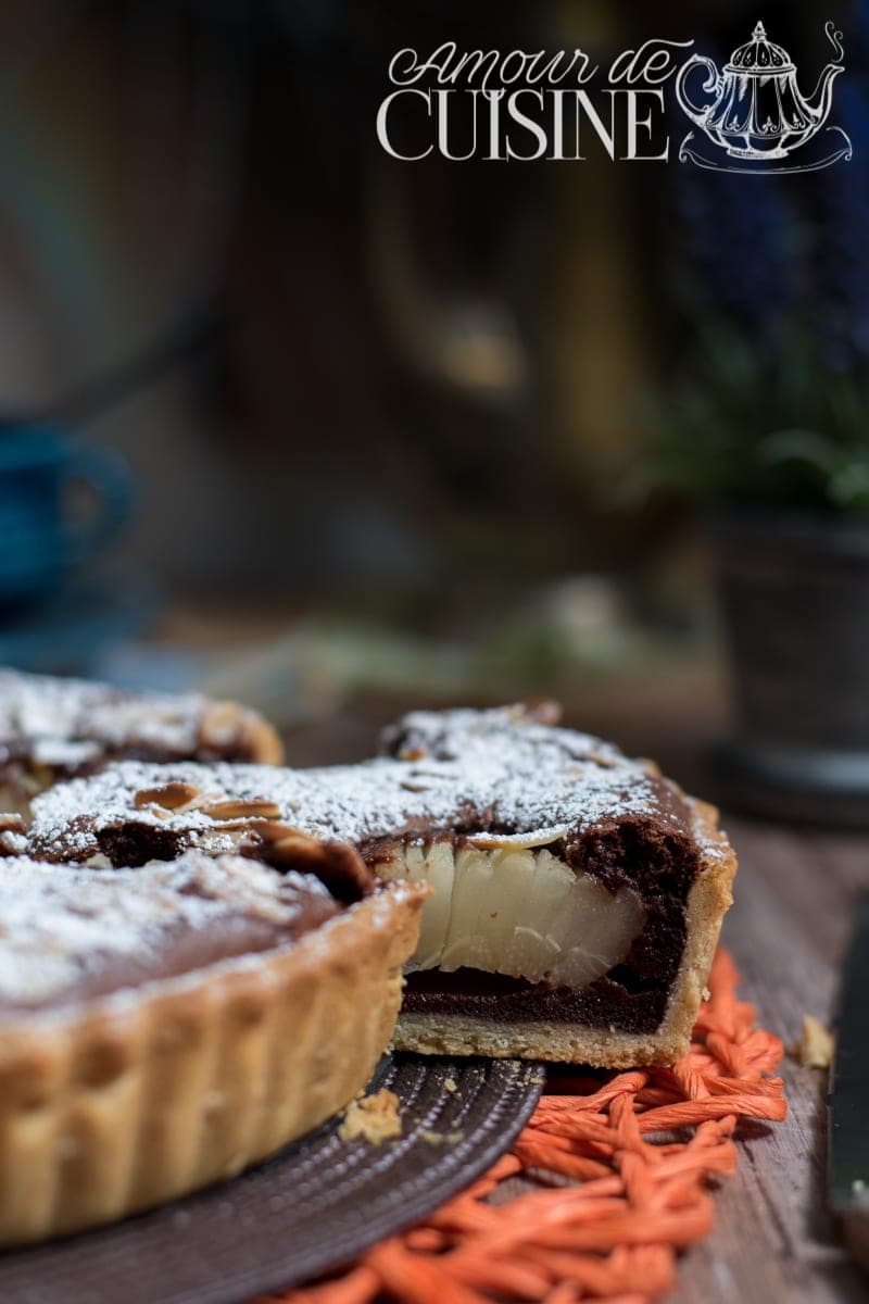 Tarte poires et chocolat de Stéphane Glacier, vue en gros plan, avec une part découpée laissant apparaître la poire fondante, la ganache chocolat brillante et la pâte sablée dorée, saupoudrée de sucre glace