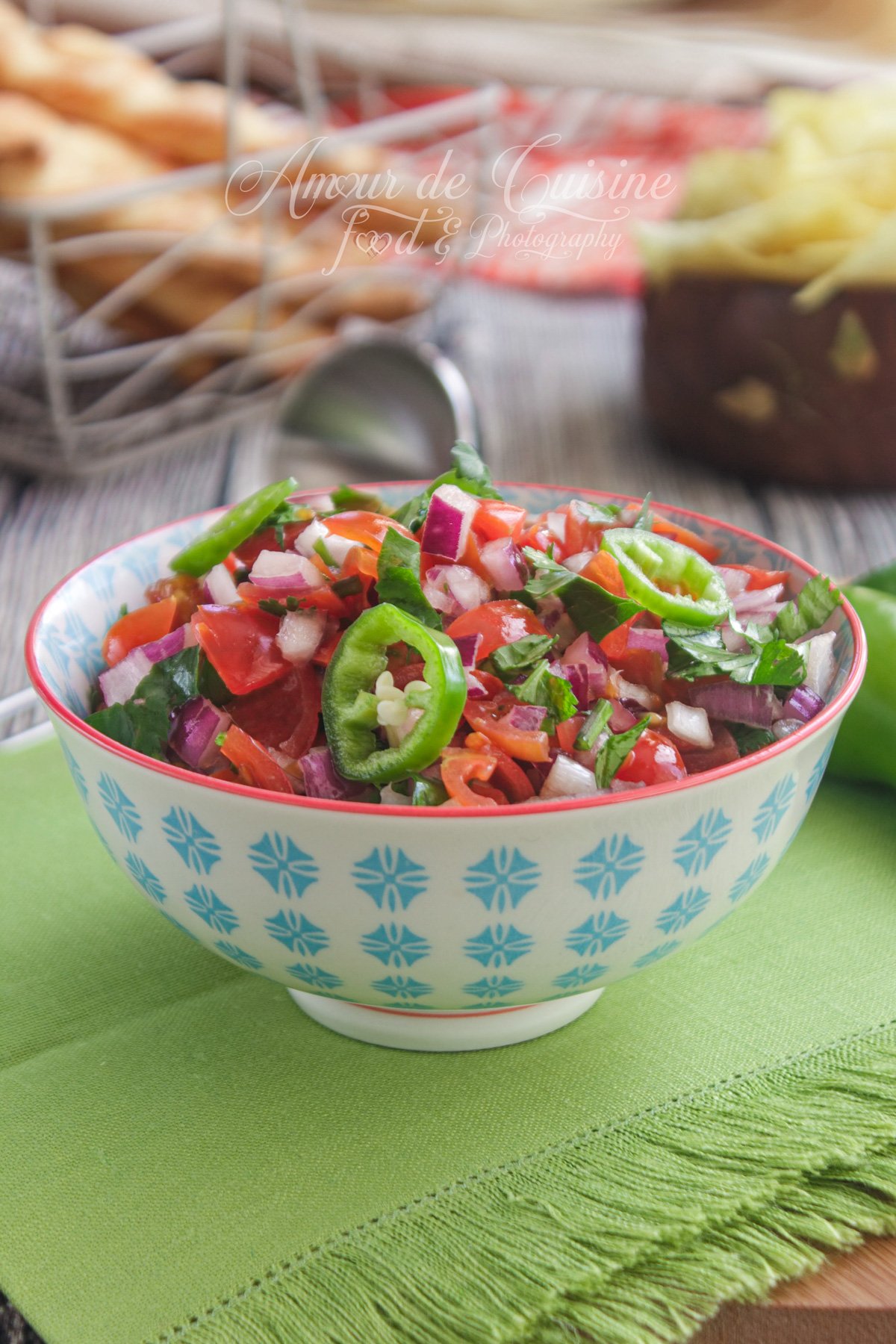 Bowl of homemade pico de gallo (fresh salsa) with diced tomatoes, red onion, cilantro and sliced green chili, photographed close-up on a green napkin.