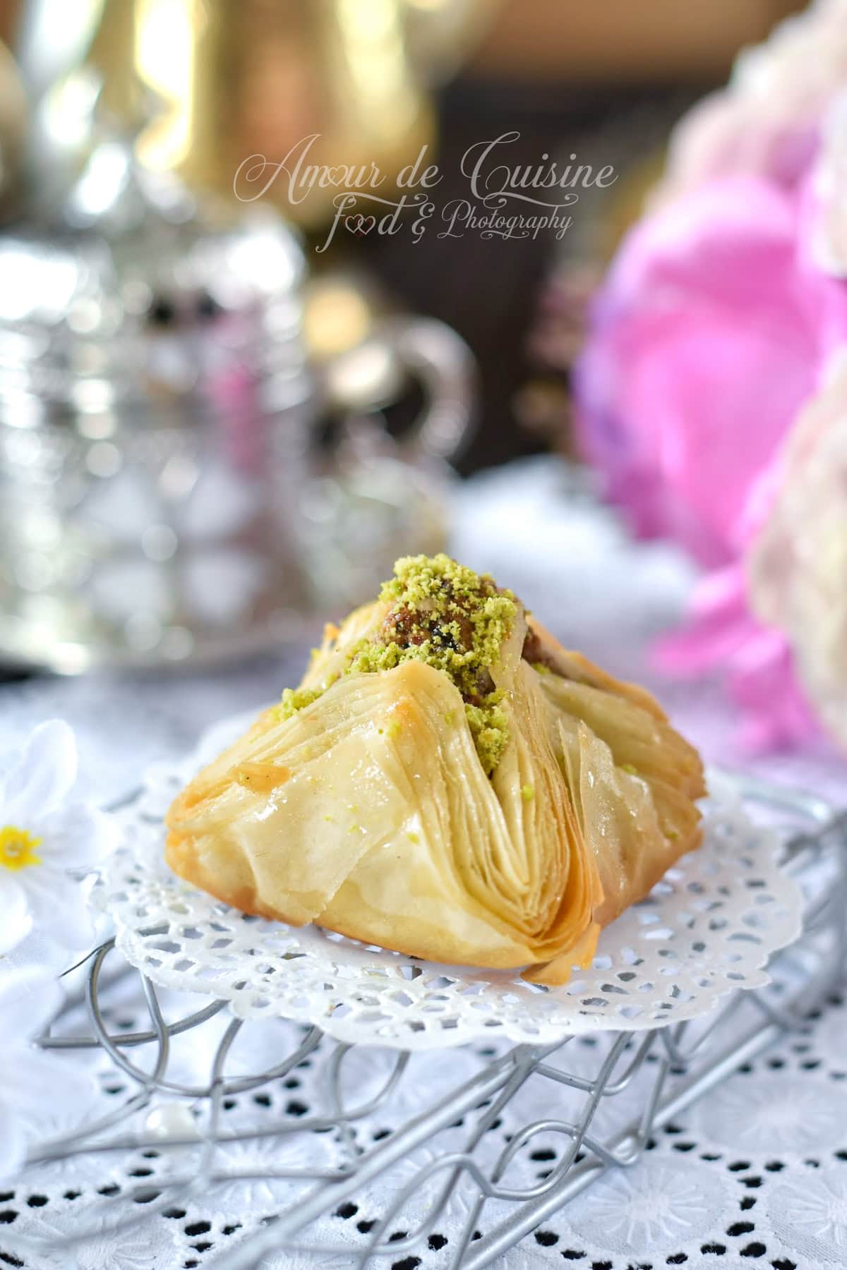 Baklawa chamiya syrienne en forme de pyramide, pâte filo dorée et croustillante, imbibée de miel, farce aux fruits secs et finition aux pistaches concassées, pâtisserie orientale maison.