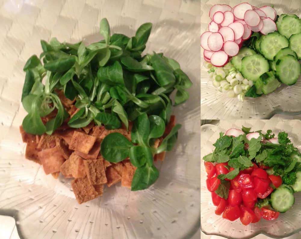 Préparation de la salade fattouche avec pain pita grillé, mâche, radis, concombre, oignons verts, tomates cerises, menthe et persil dans différents bols
