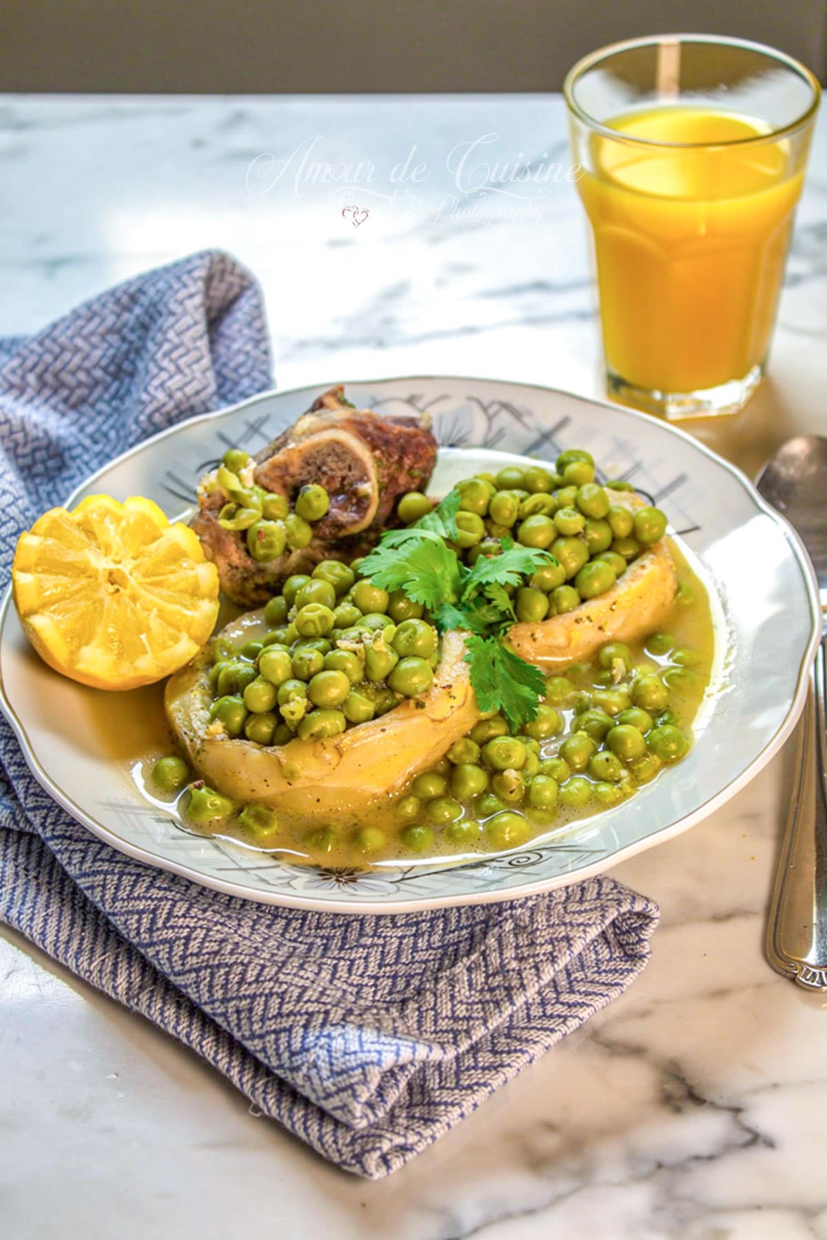 Tajine petit pois à l’agneau en sauce blanche avec artichauts, citron et persil frais, servi dans une assiette.