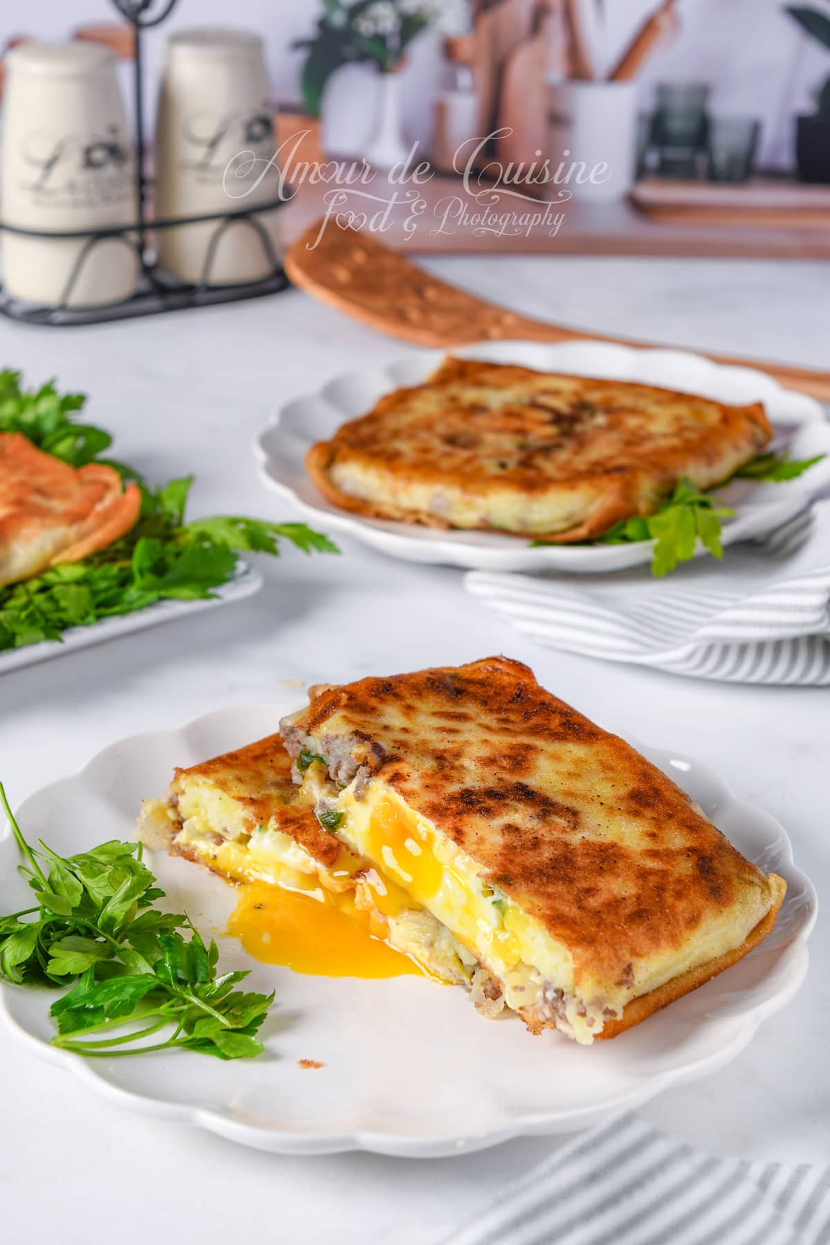 Crispy egg-filled bourek (Annabi square) cut open with a runny yolk and minced meat filling, served on a white plate with parsley in a bright kitchen setting.
