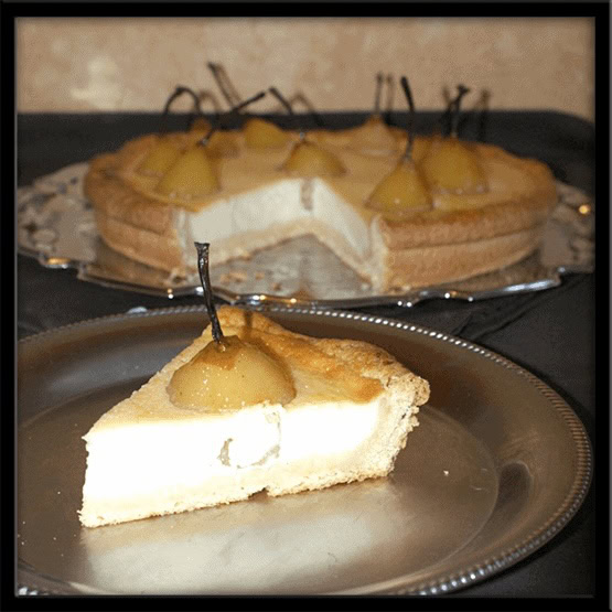 Part de clafoutis aux poires pochées servie à l’assiette, avec une crème fondante sur pâte sablée et le dessert entier en arrière-plan.