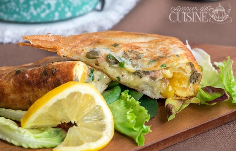Brick tunisienne à l'oeuf et au thon croustillante, servie sur un lit de salade verte avec rondelle de citron, farcie de câpres, fromage et persil.