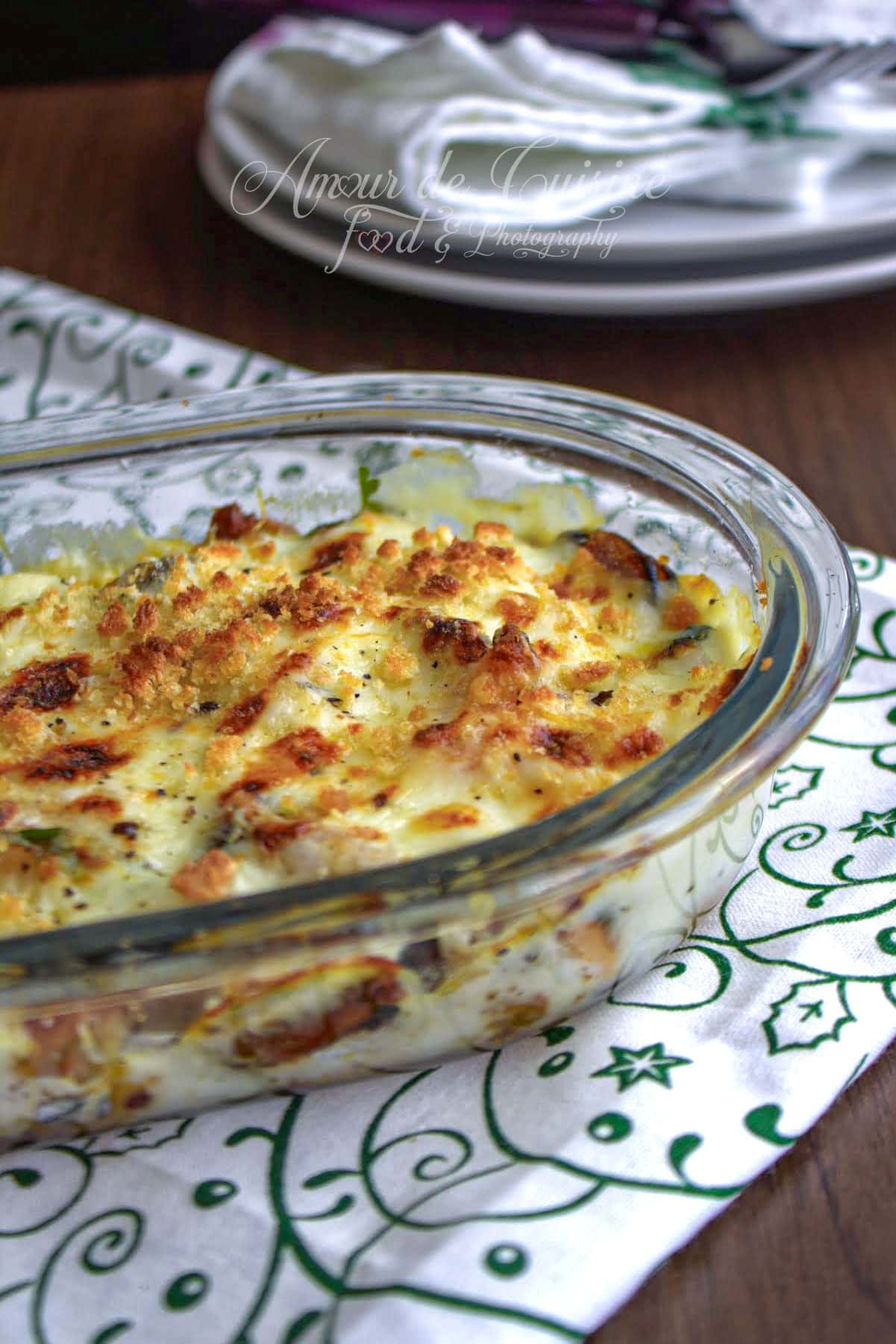 Gratin de fruits de mer maison doré au four, servi dans un plat en verre avec béchamel crémeuse et surface gratinée.