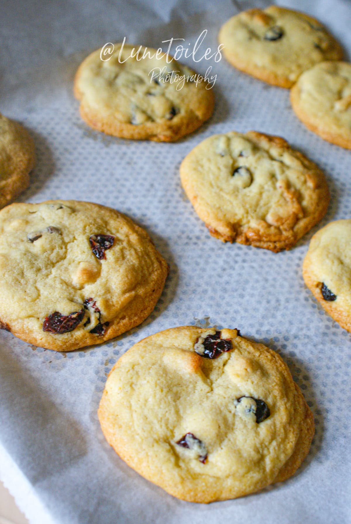 Cookies maison à la pâte d’amande et cranberries, tout juste sortis du four, disposés sur une plaque recouverte de papier cuisson
