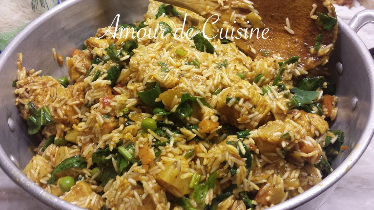 Mélange de riz basmati cru, poulet, épinards, petits pois et légumes dans une grande marmite avant cuisson vapeur pour la préparation du riz djerbien tunisien