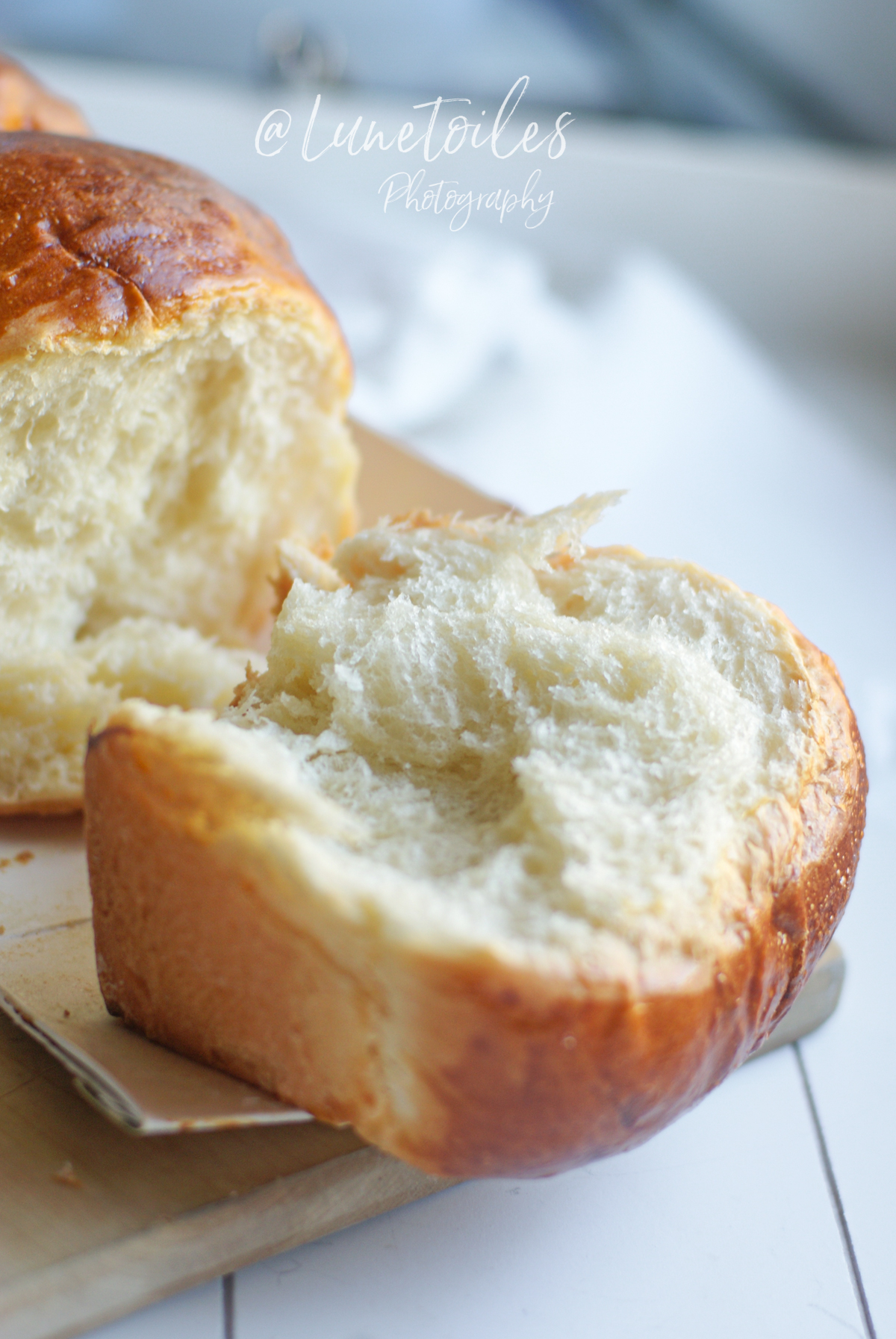 Slice of homemade Hokkaido Japanese milk bread, golden brioche with a fluffy, airy crumb, displayed on a wooden board