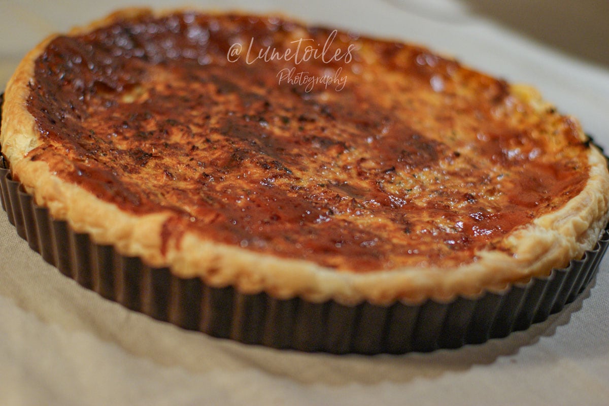 Quiche aux carottes au gouda et cumin entière, dorée au four, dans un moule à tarte.
