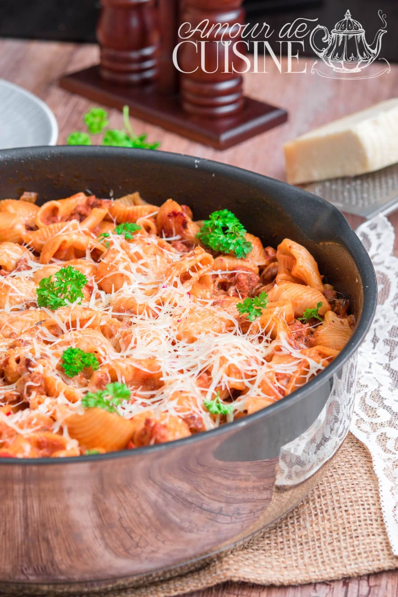Casserole of penne rigate with ground beef, simmered in tomato sauce, topped with melted grated cheese and fresh parsley, served in a large black skillet