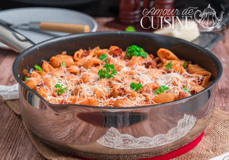 Skillet of one-pot pasta with penne rigate and ground beef, simmered in a creamy tomato sauce, topped with melted grated cheese and fresh parsley, served on a wooden table with a rustic touch