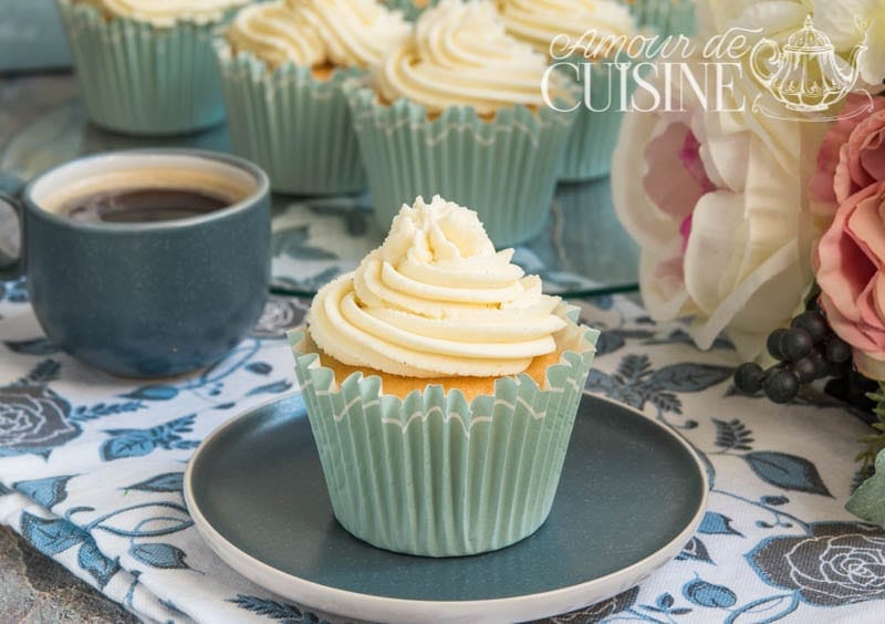 Cupcake à la ganache mascarpone au chocolat blanc, décoré d’une crème onctueuse, idéal pour layer cake, présenté sur une assiette avec une tasse de café – recette facile de glaçage chocolat blanc.