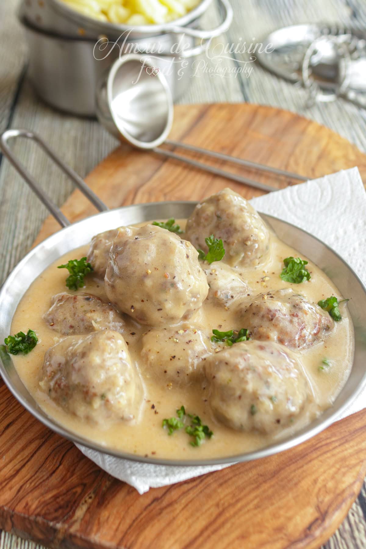 Swedish meatballs topped with creamy sauce, served in a small metal skillet, garnished with fresh parsley