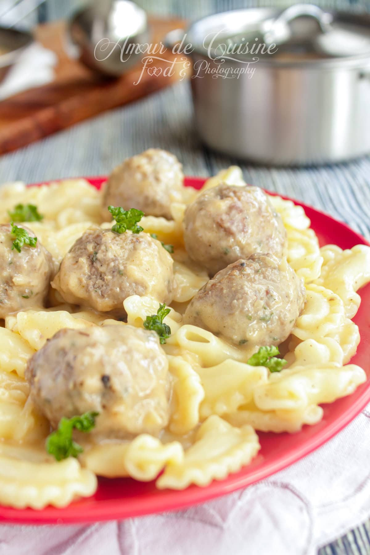 Plate of Swedish meatballs covered in creamy sauce, served with pasta and garnished with fresh parsley