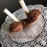 Coupe de crème glacée maison au chocolat, décorée de filets de chocolat fondu et de deux bâtonnets de chocolat blanc, servie sur une nappe en dentelle blanche