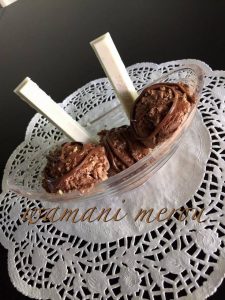 Coupe de crème glacée maison au chocolat, décorée de filets de chocolat fondu et de deux bâtonnets de chocolat blanc, servie sur une nappe en dentelle blanche