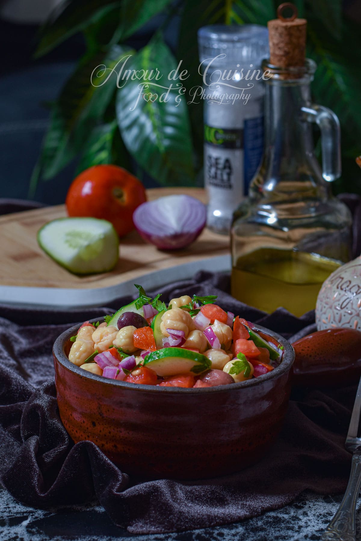 Salade de pois chiche maison avec concombre, tomates, oignon rouge, persil et olives, servie avec huile d’olive.