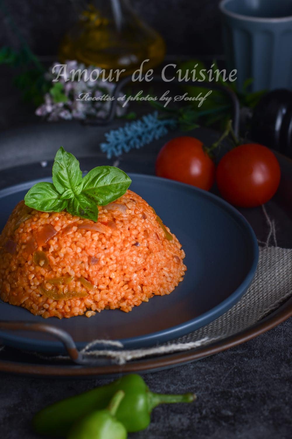Assiette de boulgour pilaf à la turque (bulgur pilavi) servie en dôme, garnie de feuilles de basilic, accompagnée de tomates fraîches et piments verts, sur une assiette foncée rustique.