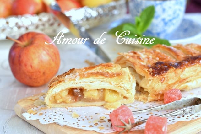 Strudel aux pommes à la pâte feuilletée, coupé en parts avec garniture fondante aux pommes et raisins secs.