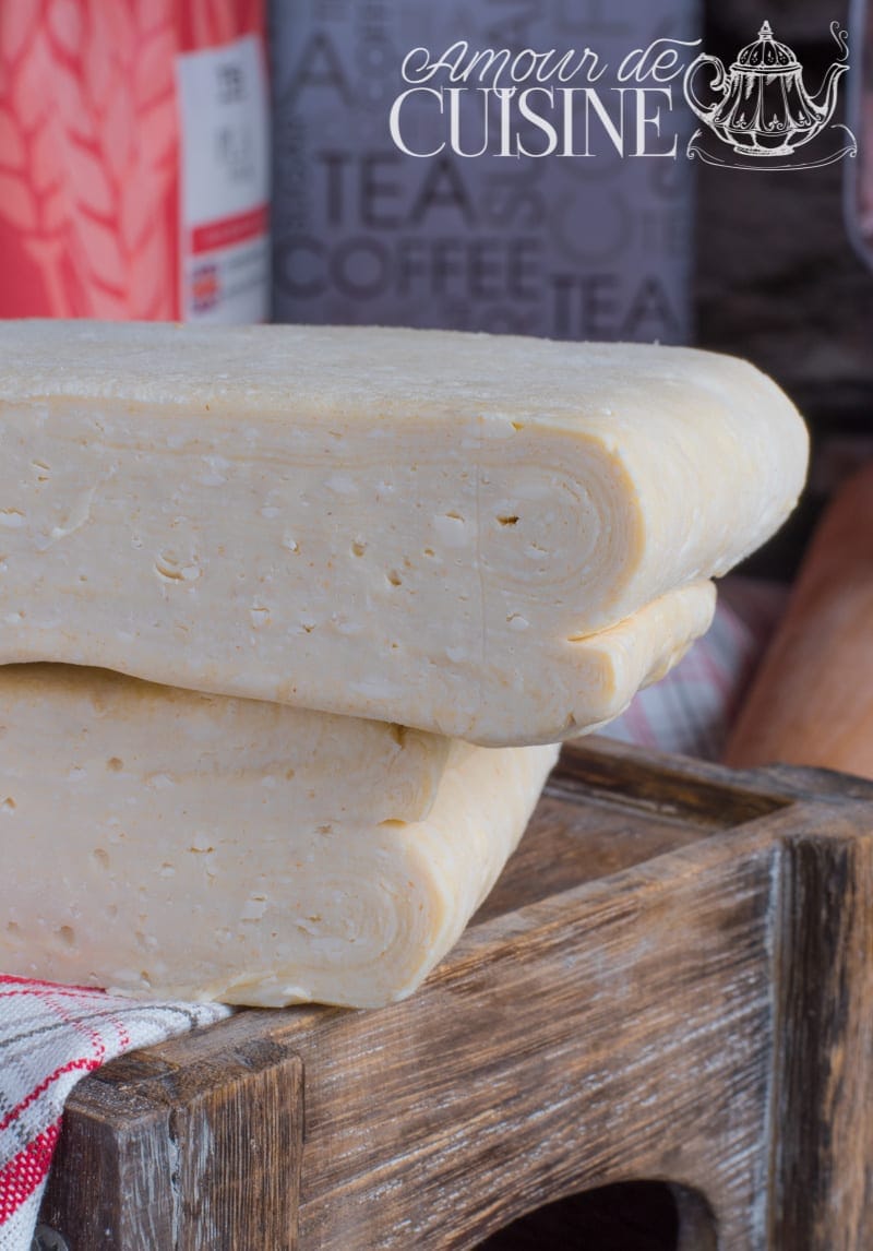 Two blocks of homemade butter puff pastry dough stacked on a wooden crate, showing the laminated layers on the cut side.