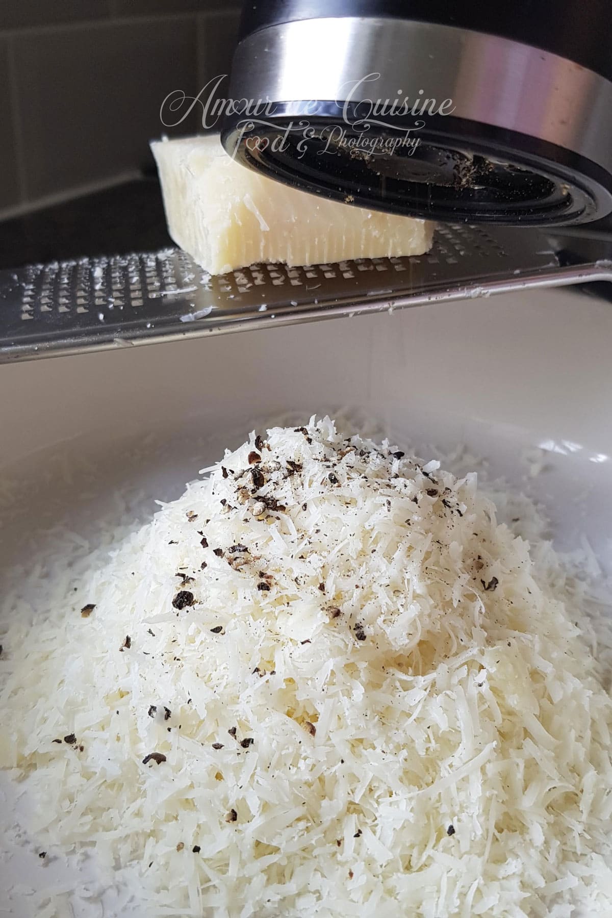 Pecorino romano fraîchement râpé avec du poivre noir, préparé pour réaliser une sauce cacio e pepe