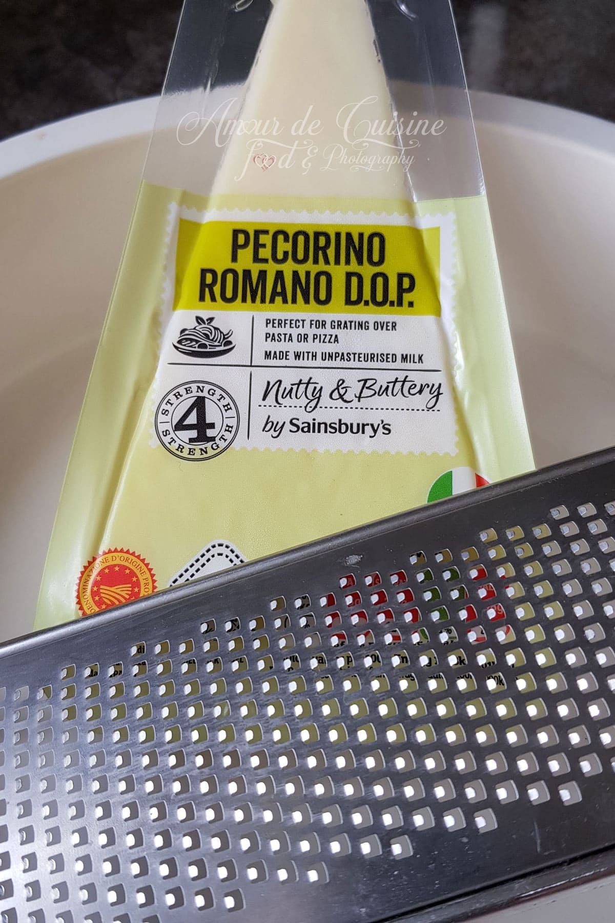 Morceau de pecorino romano avec une râpe fine, prêt à être râpé pour préparer un cacio e pepe