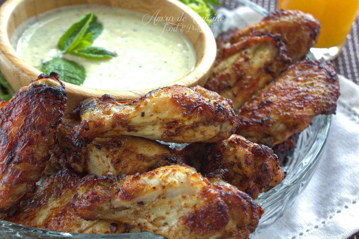 Ailes de poulet au four dorées aux épices, servies avec une sauce crémeuse à la menthe.