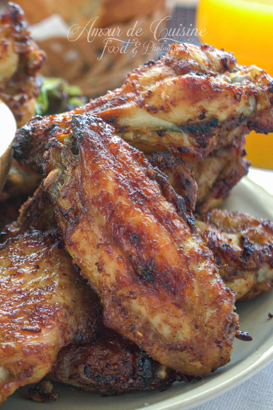 Ailes de poulet au four bien dorées et marinées aux épices, servies chaudes sur une assiette.