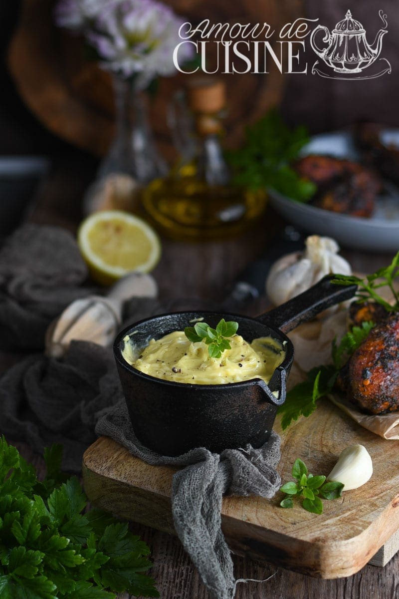 recette Aïoli Provençal Casserole en fonte remplie de sauce aïoli maison crémeuse, décorée d’herbes fraîches, avec ail, citron et huile d’olive en arrière-plan