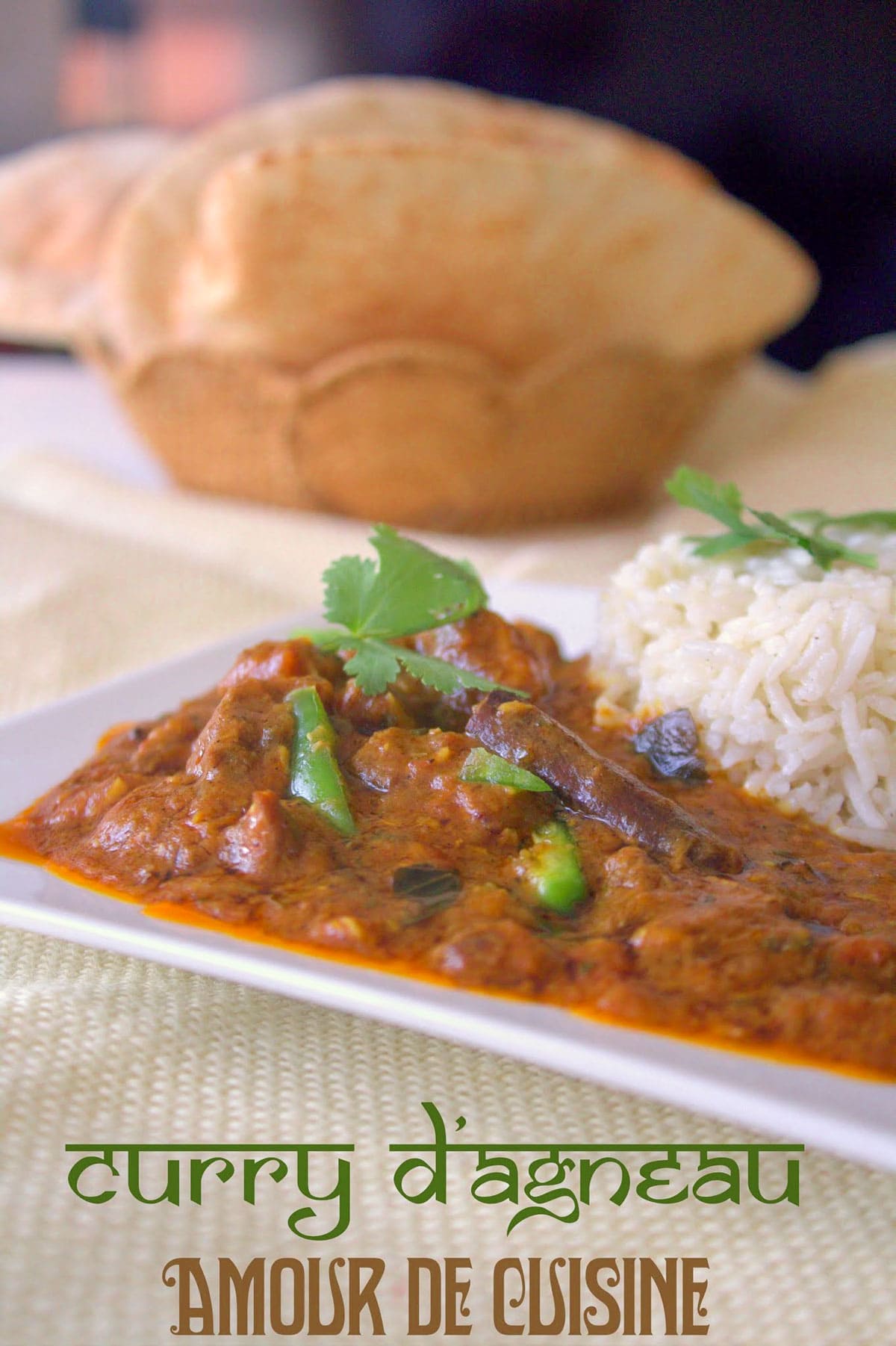 Homemade lamb curry served with basmati rice on a white plate, garnished with fresh coriander, with soft Indian bread in the background.